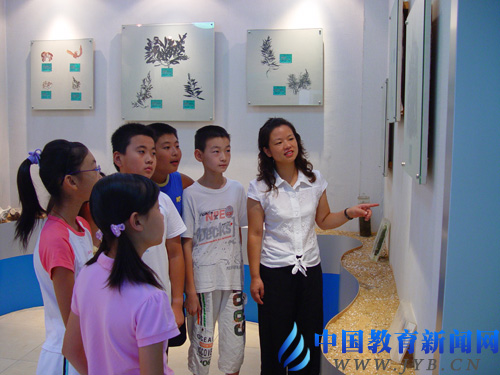 王新华（右一）在同安路小学的海洋博物馆里给学生讲解海洋知识。 资料图片
