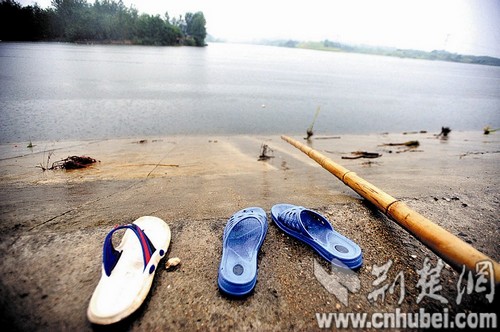 图为：坝岸边，留下救人者的拖鞋和用过的竹竿