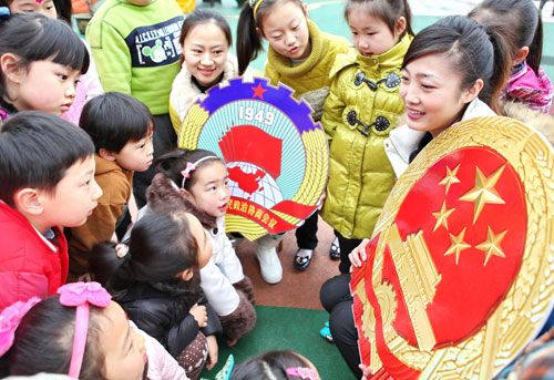 江苏徐州市鼓楼区实验幼儿园的老师在给小朋友讲解国徽和政协会徽图案的含义