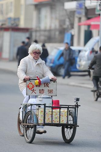 4月25日，于萍蹬着三轮车沿街卖粥。