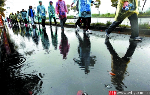 “一个鸡蛋的暴走”活动参与者行走在雨中。